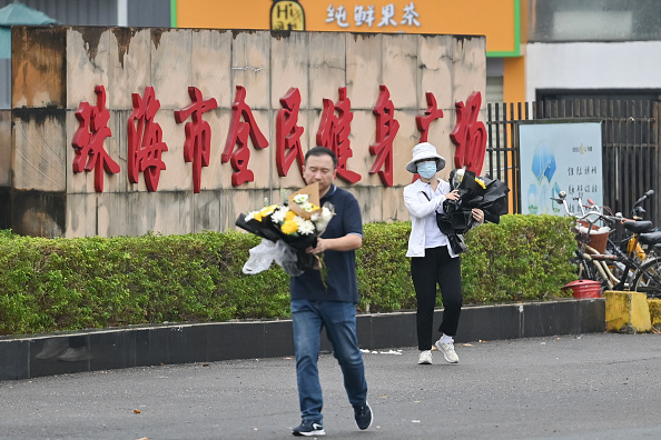 Des personnels enlèvent les fleurs d'un mémorial improvisé à l'extérieur du Centre sportif de Zhuhai, à Zhuhai, dans la province de Guangdong, en Chine, le 13 novembre 2024. (HECTOR RETAMAL/AFP via Getty Images)