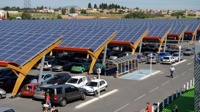 Des clients du centre commercial E.Leclerc de Saint-Aunes passent le 12 juin 2008 sur le parking du supermarché équipé de 12 rangées d'ombrières de 85 mètres de long, qui abritent 816 places de parking. (Photo : PASCAL GUYOT/AFP via Getty Images)