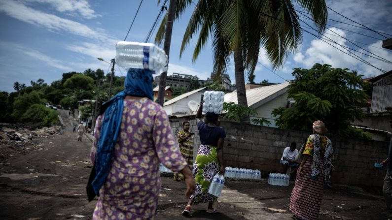 Des personnes arrivent à un point de distribution d'eau potable en bouteille dans le quartier de Majicavo à Mamoudzou, sur l'île de Mayotte, le 19 février 2024. (JULIEN DE ROSA/AFP via Getty Images)