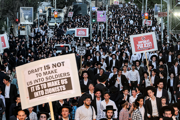 Des manifestants juifs ultra-orthodoxes se rassemblent pour protester contre une décision de la Haute Cour israélienne selon laquelle ils doivent être incorporés dans le service militaire, dans le quartier de Mea Sharim à Jérusalem, le 30 juin 2024. La plupart des hommes et des femmes juifs d'Israël doivent faire leur service militaire, mais depuis 1948, la communauté ultra-orthodoxe insulaire bénéficie d'exemptions de service militaire afin que certains étudiants puissent poursuivre leurs études à la yeshiva. Au fil des ans, la communauté ultra-orthodoxe, ou Haredi, a grossi, et avec elle le nombre d'exemptions. (AHMAD GHARABLI/AFP via Getty Images)