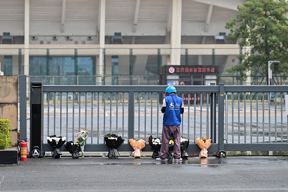 Un livreur dépose des bouquets de fleurs commandés en ligne sur un mémorial improvisé à l'extérieur du Centre sportif de Zhuhai le 13 novembre 2024, deux jours après que 35 personnes ont été tuées par un homme qui a foncé dans la foule au volant d'une voiture. (HECTOR RETAMAL/AFP via Getty Images)