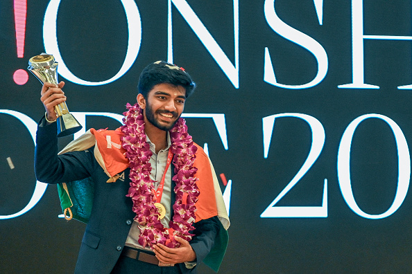 L'Indien Gukesh Dommaraju célèbre avec le trophée du Championnat du monde d'échecs 2024 après avoir battu le Chinois Ding Liren, lors d'une cérémonie de remise des prix du Championnat du monde d'échecs 2024 à Singapour, le 13 décembre 2024. (SIMON LIM/AFP via Getty Images)