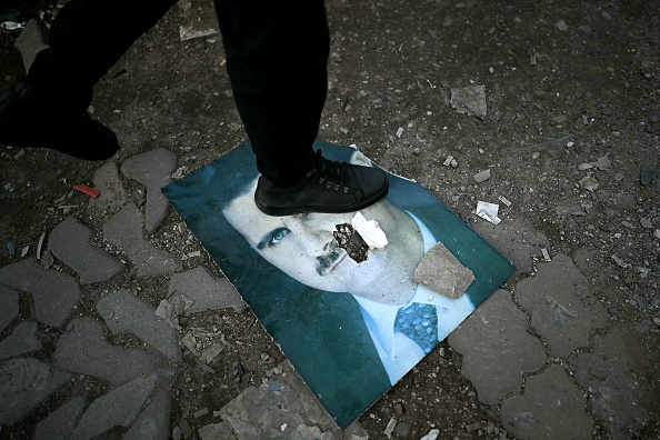 Un homme marche sur un portrait endommagé du président syrien déchu Bashar al-Assad dans la ville portuaire de Latakia, dans l'ouest de la Syrie, le 15 décembre 2024. (OZAN KOSE/AFP via Getty Images)