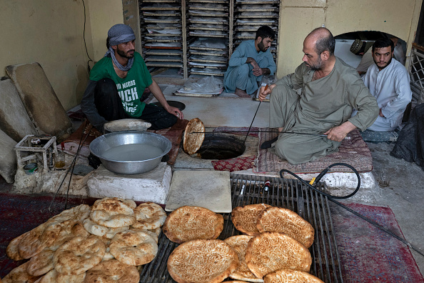 Cette photographie prise le 27 novembre 2024 montre le boulanger afghan Jamil Ghafori (à gauche) préparant des pains plats traditionnels connus localement sous le nom de Naan, dans une boulangerie de Kaboul.  (WAKIL KOHSAR/AFP via Getty Images)