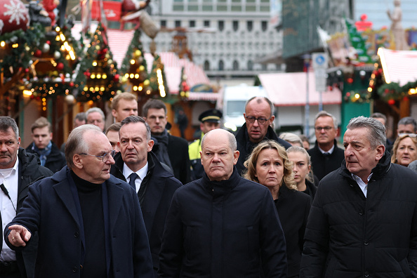 Le chancelier allemand Olaf Scholz (au c., premier rang), le Premier ministre du Land de Saxe-Anhalt Reiner Haseloff (à g., premier rang), le ministre allemand des Transports et des Affaires numériques et de la Justice Volker Wissing (à g., deuxième rang), la ministre allemande de l'Environnement, de la Protection de la nature, de la Sécurité nucléaire et de la Protection des consommateurs Steffi Lemke (à dr., deuxième rang) visitent le lieu de l'attaque à la voiture piégée sur le marché de Noël de Magdebourg. (RONNY HARTMANN/AFP via Getty Images)