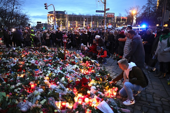 Des personnes déposent des fleurs devant un mémorial improvisé près du marché de Noël fermé, au lendemain d'un attentat terroriste qui a fait cinq morts, dont un petit enfant, et plus de 200 blessés, le 21 décembre 2024 à Magdebourg, en Allemagne. (Photo Omer Messinger/Getty Images)