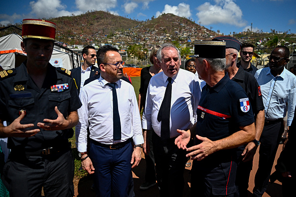 Le Premier ministre François Bayrou (au c.) et le ministre en charge de la santé et de l'accès aux soins Yannick Neuder (2e à g.) marchent lors d'une visite à Mamoudzou, le 30 décembre 2024. (JULIEN DE ROSA/AFP via Getty Images)