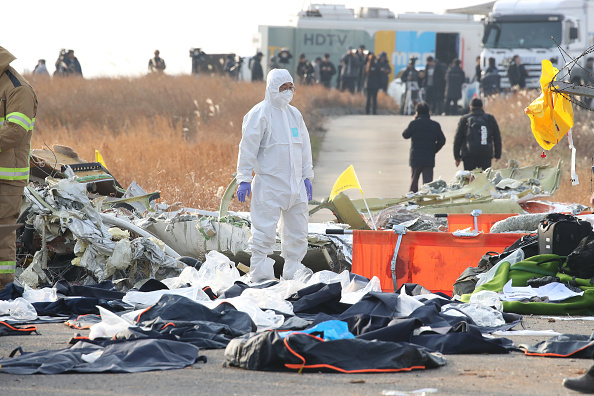 Des membres de l'équipe de secours sud-coréenne vérifient près de l'épave d'un avion de passagers à l'aéroport international de Muan le 29 décembre 2024 à Muan-gun, en Corée du Sud. (Photo Chung Sung-Jun/Getty Images)