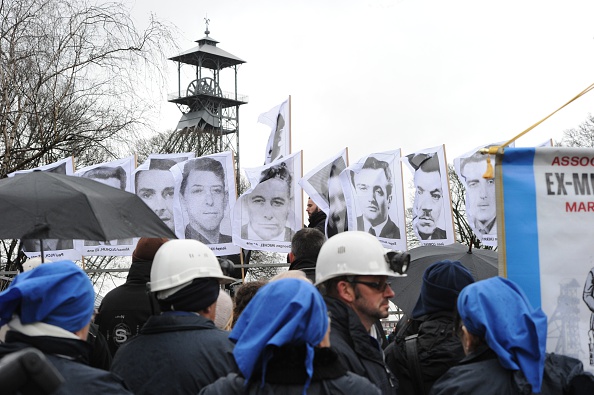 Des mineurs tiennent les portraits des 42 victimes de la catastrophe minière de Lievin dans le Pas-de-Calais, le 27 décembre 2014. (PHILIPPE HUGUEN/AFP via Getty Images)