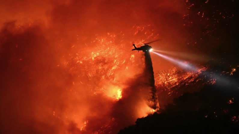 Un hélicoptère de lutte contre les incendies largue de l'eau alors que l'incendie de Palisades prend de l'ampleur près du quartier de Mandeville Canyon et d'Encino, en Californie, le 11 janvier 2025. (Patrick T. Fallon/AFP via Getty Images)