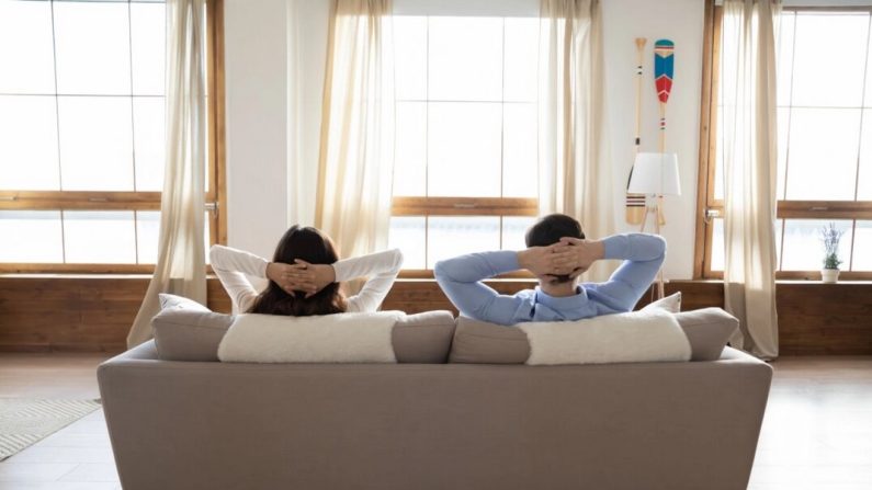 Un jeune couple se détend sur un canapé. (Shutterstock)