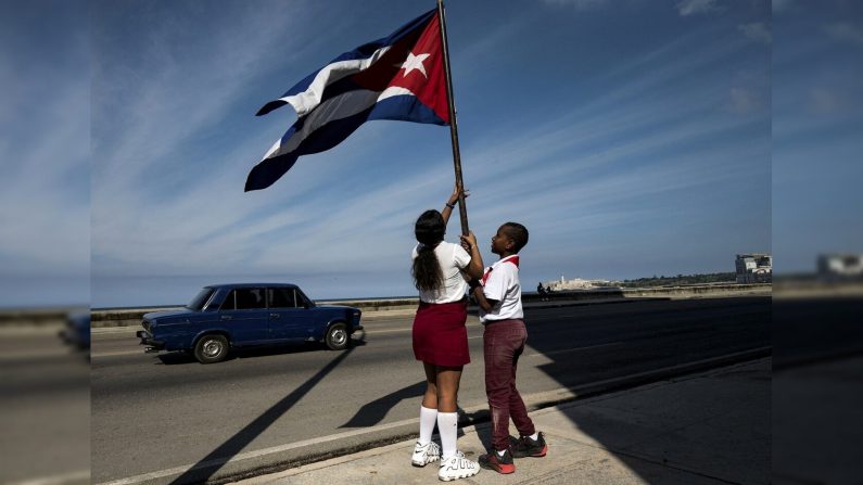 Deux jeunes pionniers cubains brandissent un drapeau national en attendant le défilé commémorant le 65e anniversaire de l'entrée de Fidel Castro à La Havane, le 8 janvier 2024. (YAMIL LAGE/AFP via Getty Images)