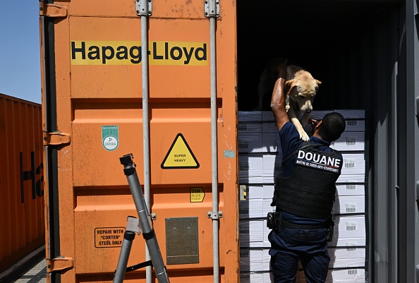 Un douanier transporte un chien renifleur d'un conteneur de camion dans le port de Fos-sur-Mer, dans le sud-est de la France, le 4 juillet 2022.  (CHRISTOPHE SIMON/AFP via Getty Images)