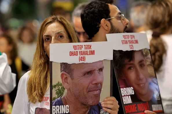 Des personnes portent des affiches avec les images de Ohad, 49 ans, et Eitan Yahalomi, 12 ans, le 11 novembre 2023, lors d'une manifestation à Tel Aviv. (AHMAD GHARABLI/AFP via Getty Images)