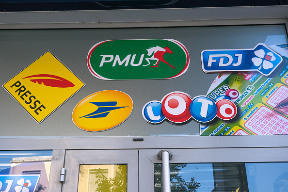 Des autocollants représentant les logos et dessins des jeux de La Française des Jeux, La Poste et La Plume de la Presse sur la devanture d'un tabac presse, le 2 août 2024. (NICOLAS GUYONNET/Hans Lucas/AFP via Getty Images)