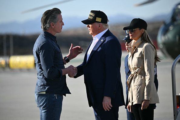 Le Président américain Donald Trump, suivi de la Première dame Melania Trump, serre la main du gouverneur de Californie Gavin Newsom à son arrivée à Los Angeles en Californie, le 24 janvier 2025. (MANDEL NGAN/AFP via Getty Images)