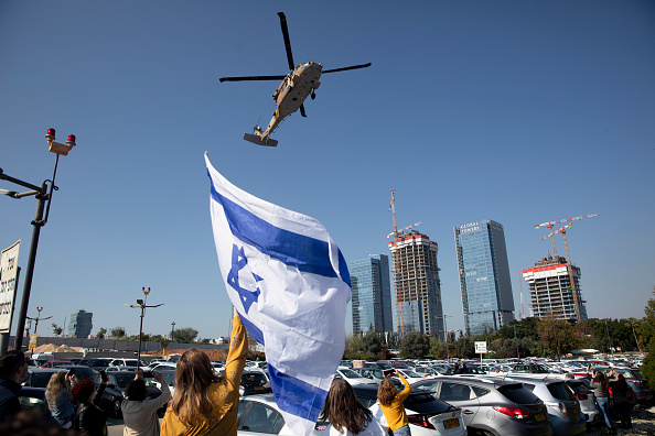 Une femme tient un drapeau israélien alors qu'un hélicoptère de l'armée transportant l'otage Agam Berger, récemment libéré, atterrit à l'hôpital Beilinson le 30 janvier 2025 à Petah Tikva, Israël. (Amir Levy/Getty Images)