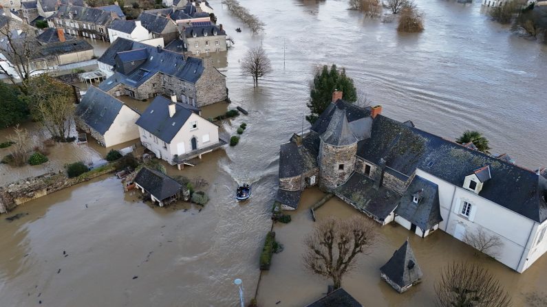 Des CRS se déplacent à bord d'un bateau pneumatique vers des maisons envahies par les eaux à Guipry-Messac, dans l'ouest de la France, après le passage de la tempête Herminia, le 28 janvier 2025. (DAMIEN MEYER/AFP via Getty Images)