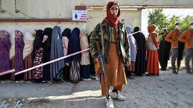 Un combattant taliban monte la garde alors que des femmes font la queue lors d'une distribution de nourriture du Programme alimentaire mondial à Kaboul, le 6 novembre 2021. (HECTOR RETAMAL/AFP via Getty Images)