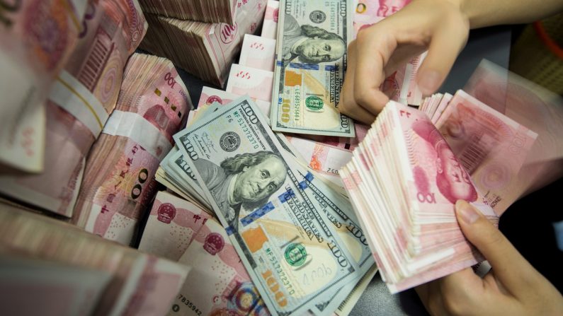 Une employée de banque chinoise compte les billets de 100 yuans et les billets de dollars américains au guichet d'une banque à Nantong, dans la province chinoise du Jiangsu (Est), le 28 août 2019. (AFP via Getty Images)