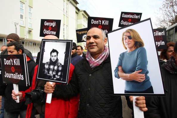 Un journaliste turc à Ankara, le 24 février 2012, tient des photos de deux journalistes, le photojournaliste français Remi Ochlik (à g.) et la correspondante du Sunday Times Marie Colvin, tués dans une attaque présumée à la roquette par les forces du régime syrien contre un centre de médias d'opposition improvisé dans la ville assiégée de Homs en Syrie le 22 février, lors d'une manifestation de journalistes dénonçant la violence contre les membres des médias et la brutalité du régime du président syrien Bashar al-Assad. (ADEM ALTAN/AFP via Getty Images)