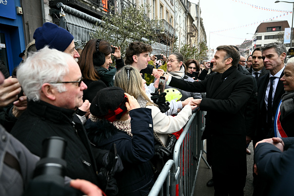 Le président français Emmanuel Macron salue les gens dans la rue après avoir assisté à la cérémonie de commémoration du 80e anniversaire de la libération par les Alliés de la ville de Colmar, le 2 février 2025. (Crédit photo SEBASTIEN BOZON/AFP via Getty Images)