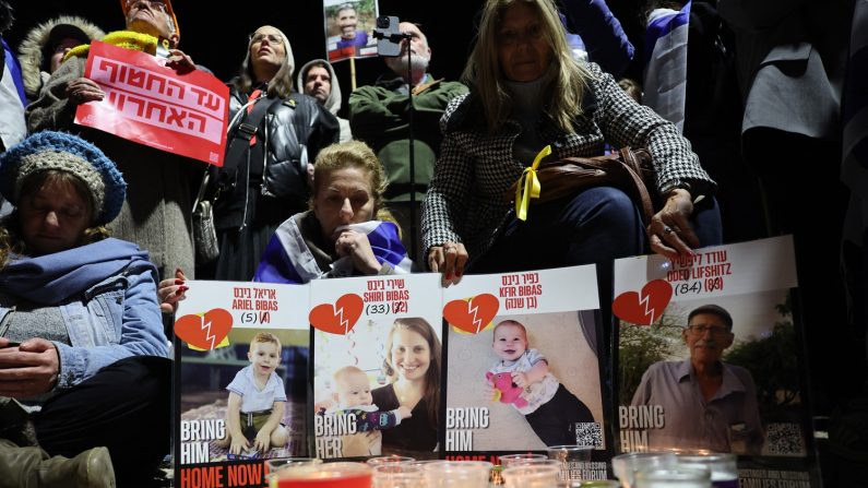 Des personnes se rassemblent derrière les affiches de quatre otages israéliens, quelques heures après que quatre corps ont été remis à Israël par le Hamas, lors d'une veillée aux chandelles organisée en leur honneur sur la place des otages à Tel Aviv, le 20 février 2025. Le 20 février, le Hamas a remis à Israël les corps de quatre otages, dont, selon le groupe, ceux de la famille Bibas, qui sont devenus les symboles de la crise des otages qui sévit en Israël depuis le déclenchement de la guerre de Gaza (JACK GUEZ/AFP via Getty Images). 