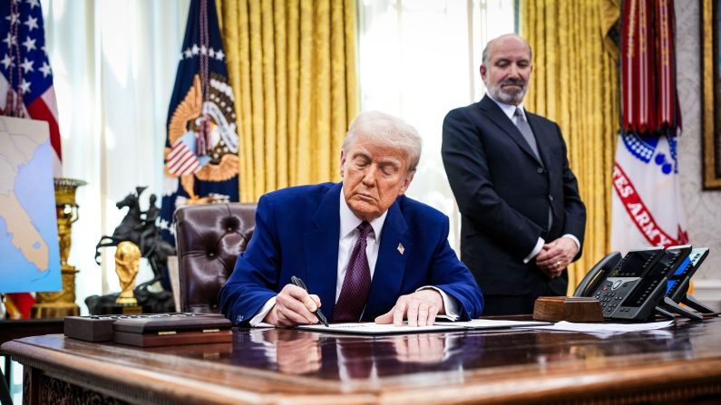 Le président Donald Trump, accompagné du candidat au poste de secrétaire au Commerce Howard Lutnick, signe un décret sur les droits de douane mutuels dans le Bureau ovale, le 13 février 2025. (Andrew Harnik/Getty Images)