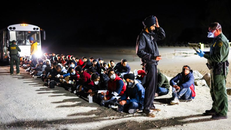 Des immigrés clandestins attendent de monter dans un bus de la police des frontières américaine pour être pris en charge après avoir traversé la frontière depuis le Mexique, à Yuma, en Arizona, le 22 mai 2022. (Mario Tama/Getty Images)