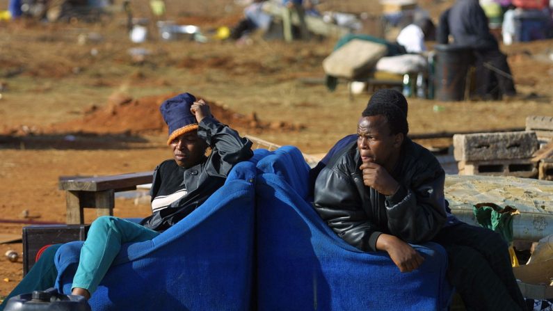 Des squatters sud-africains sont assis près de leurs biens, après que des ouvriers ont démoli leurs cabanes à la suite d'une décision de la Haute Cour de Pretoria de les expulser de terres publiques et privées, près de Johannesburg, le 13 juillet 2001. (Yoav Lemmer/AFP via Getty Images)