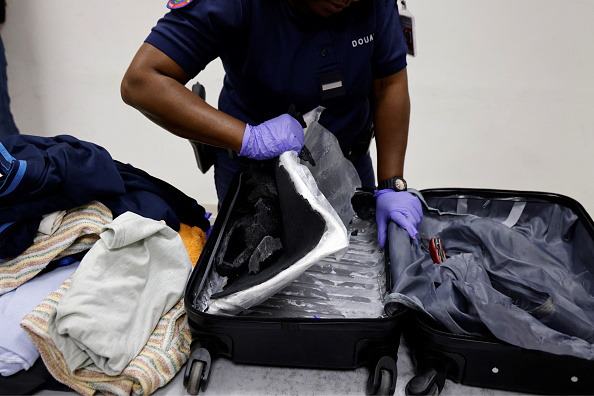 Des douaniers français découvrent de la cocaïne cachée dans une valise alors qu'ils inspectent les bagages d'un passager se rendant à Paris depuis Cayenne à l'aéroport international de Cayenne, en Guyane française, le 24 mars 2024. (LUDOVIC MARIN/AFP via Getty Images)