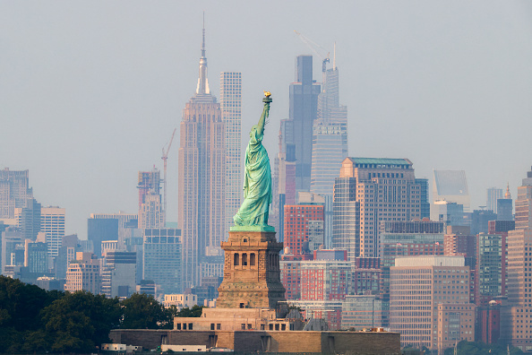 L'emblématique Empire State Building (au c. à g.) se détache sur l'horizon de Manhattan avec la Statue de la Liberté au premier plan, vue de Bayonne, New Jersey, le 15 août 2024. (Photo CHARLY TRIBALLEAU/AFP via Getty Images)