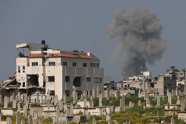 De la fumée s'élève derrière un cimetière après des frappes israéliennes à l'ouest de Gaza le 18 mars 2025. (OMAR AL-QATTAA/AFP via Getty Images)