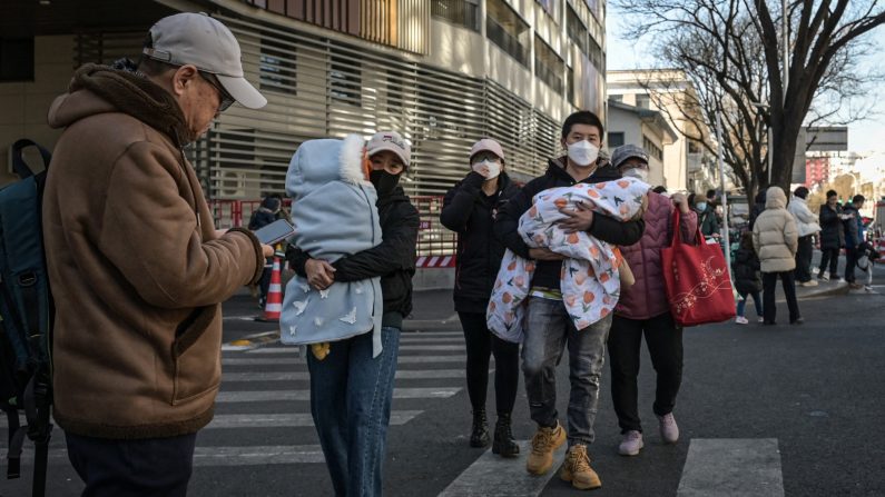 Des personnes portant leurs enfants sortent d'un hôpital pour enfants à Pékin le 10 janvier 2025. (Jade Gao/AFP via Getty Images)