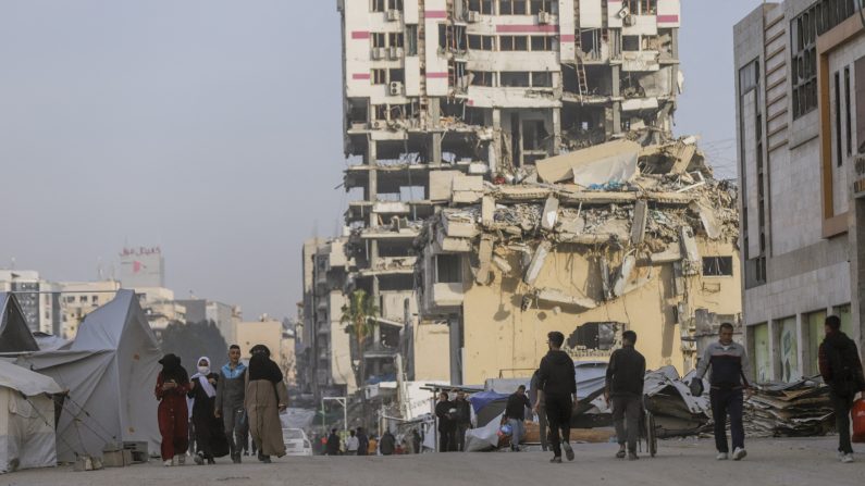 Des résidents déplacés passent devant des tentes et des bâtiments endommagés dans la ville de Gaza le 25 mars 2025. (SAEED JARAS/Middle East Images/AFP via Getty Images)