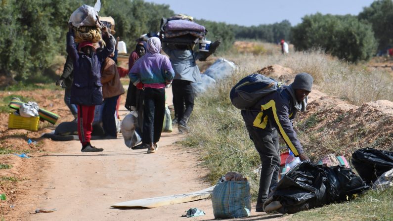 Des migrants quittent avec leurs affaires un camp de sans-papiers d'Afrique subsaharienne à al-Amra, dans la banlieue de la ville portuaire tunisienne de Sfax, le 5 avril 2025, après que les autorités ont commencé à démanteler le camp. (Photo FETHI BELAID/AFP via Getty Images)